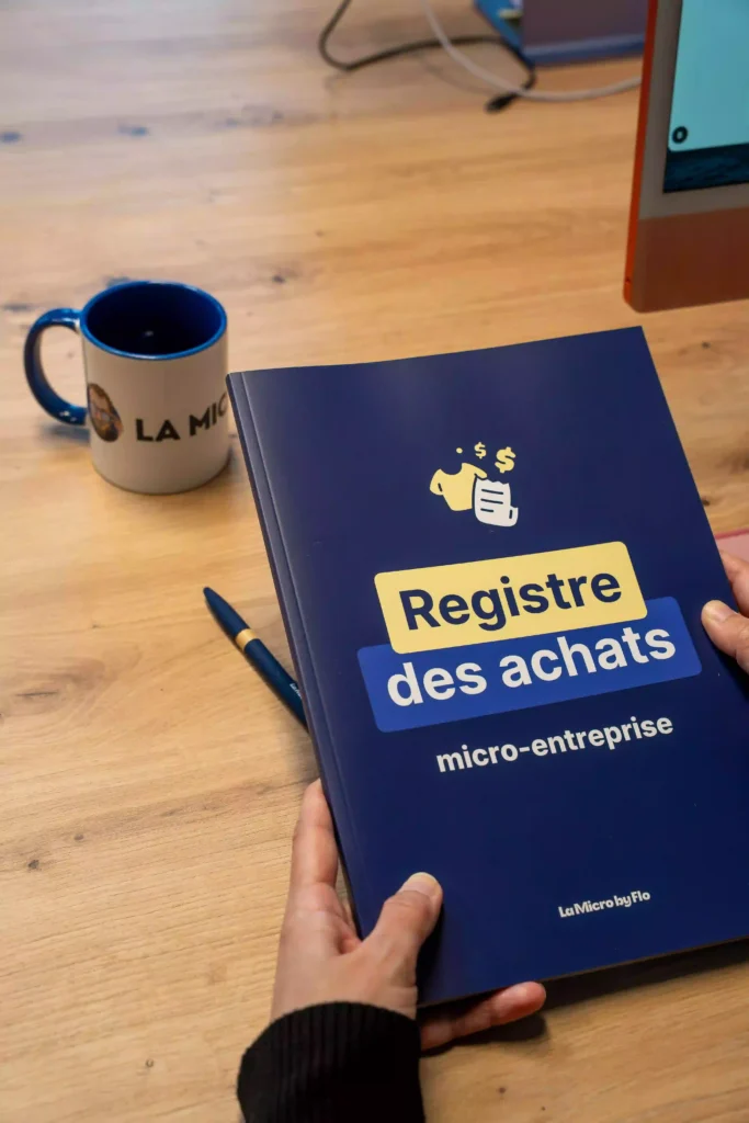 Registre des achats micro-entreprise LA MICRO BY FLO sur un bureau avec mug et stylo